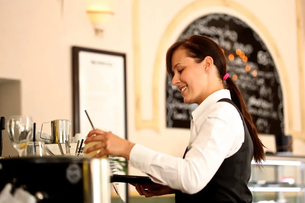 Working the coffee machine behind the counter, with the day's board chalked up behind