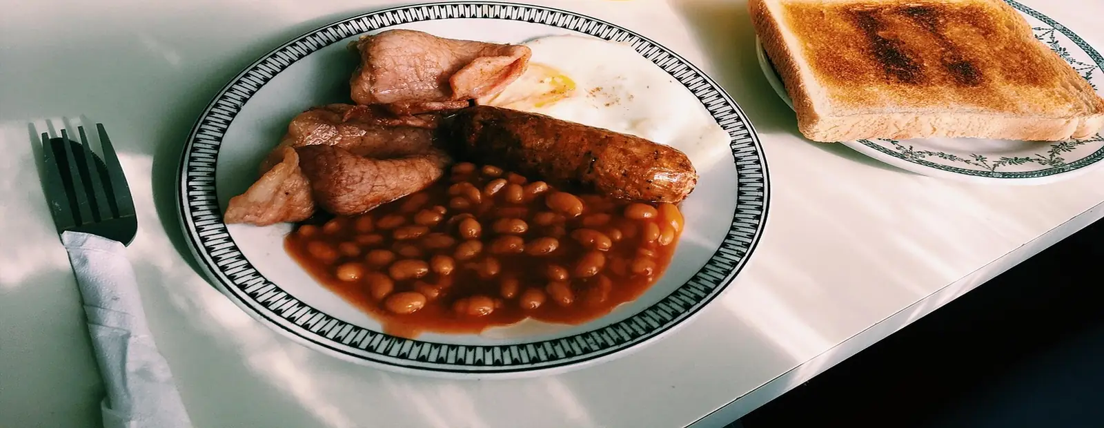 The Big Fern: bacon, square sausage, beans and a fried egg on a patterned plate