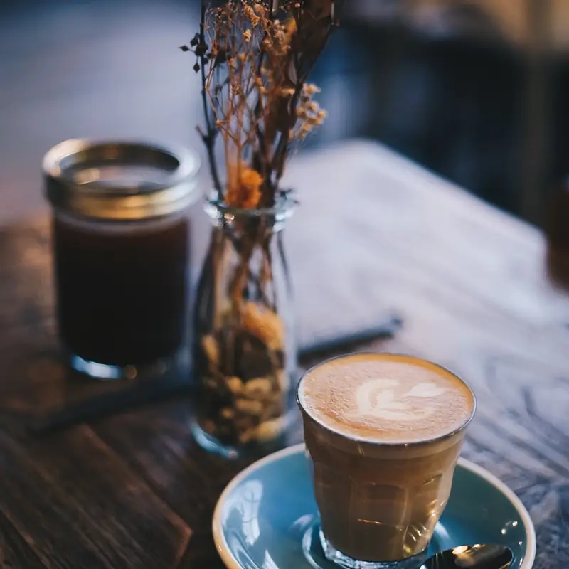 A flat white on a saucer on the dark wooden counter