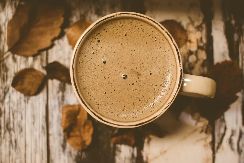 A mug of coffee seen from above on a bare wooden table