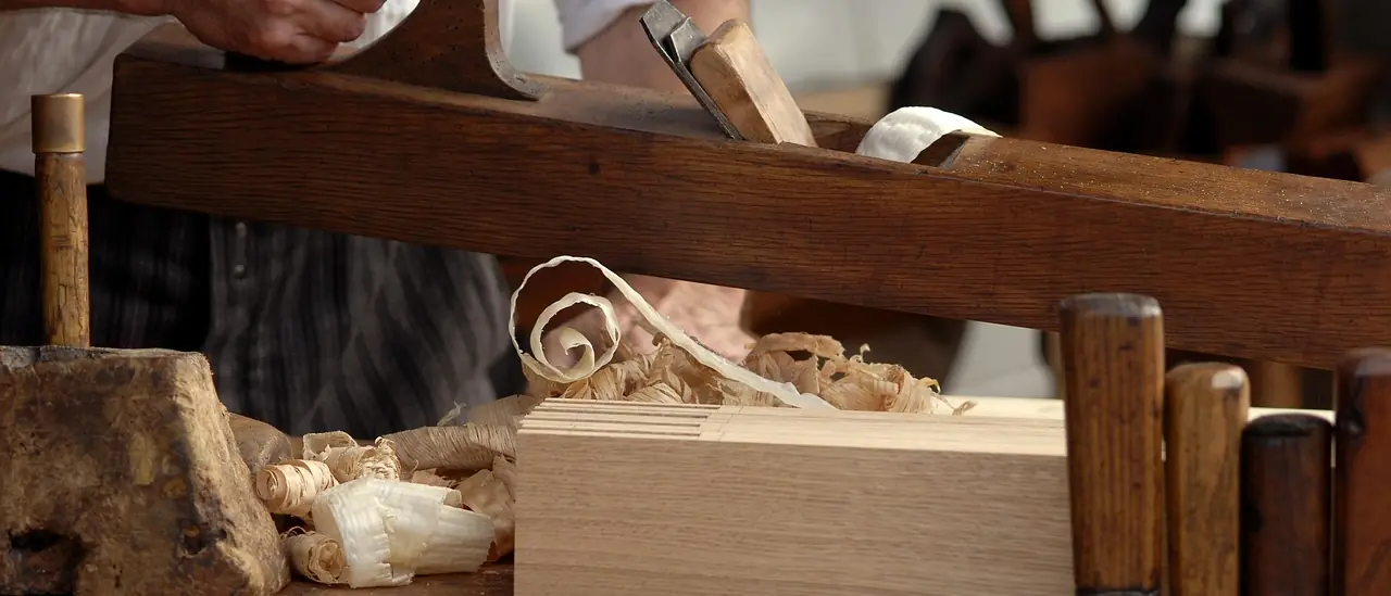 A joiner's bench with a hand plane, chisels in a rack and shavings across the boards