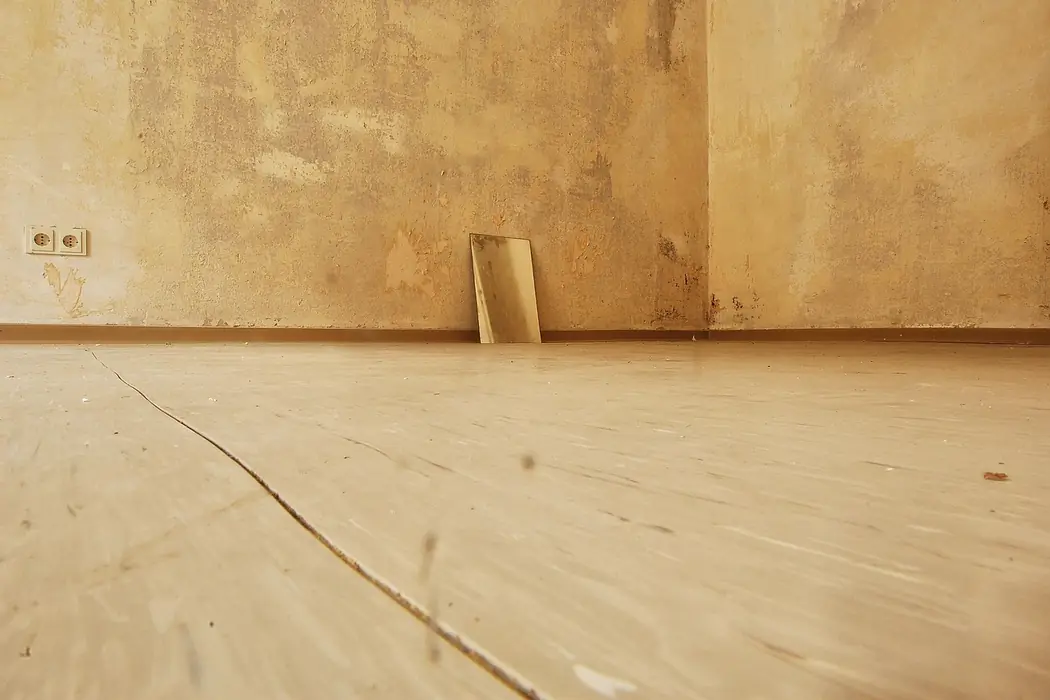 An empty room with new floorboards down and bare plaster on the walls