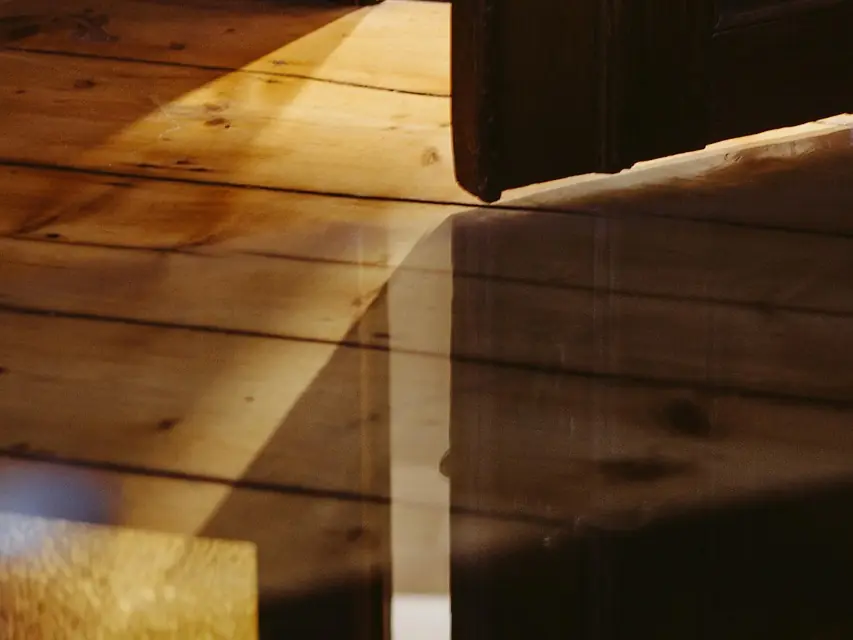 Light falling across the edge of a wooden door and the floorboards below it