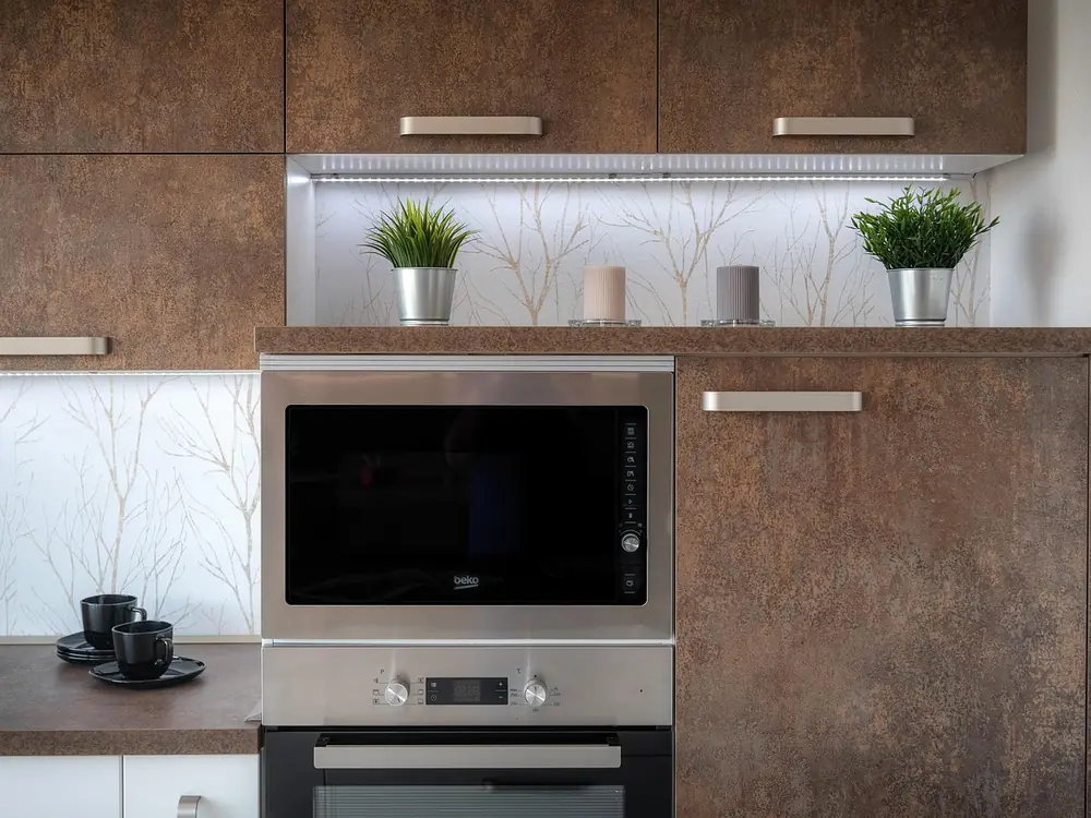 A fitted kitchen in dark brown units with an integrated oven and microwave