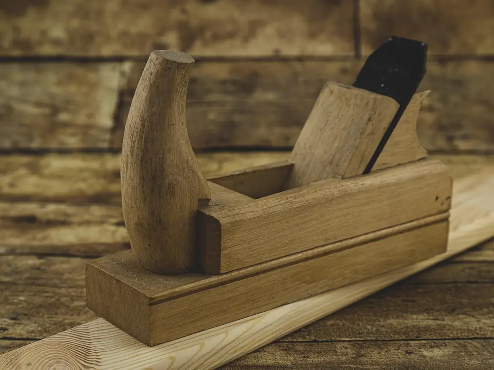 A wooden hand plane resting on a length of planed timber