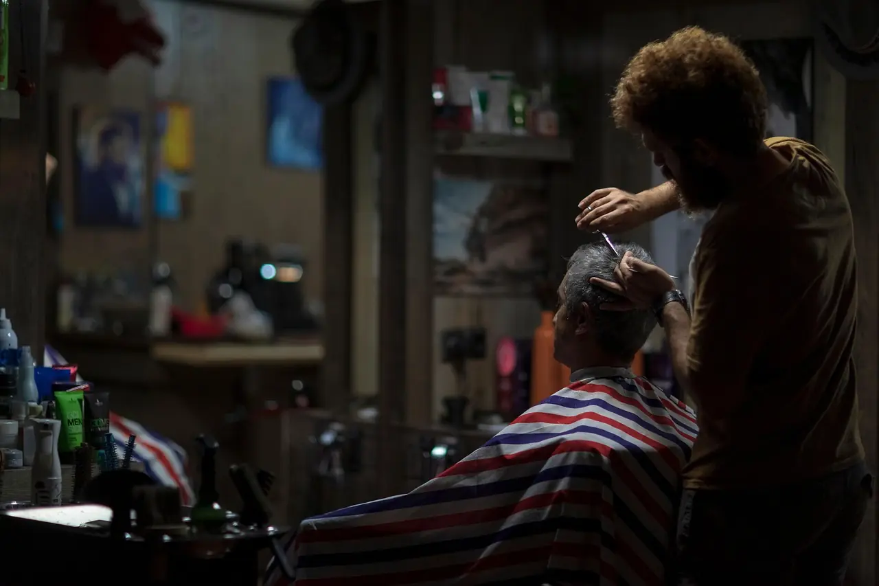 A barber cutting an older man's hair in a dimly lit Glasgow barbershop