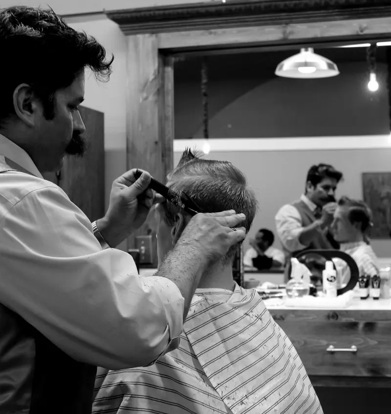 A barber cutting hair with scissors and comb