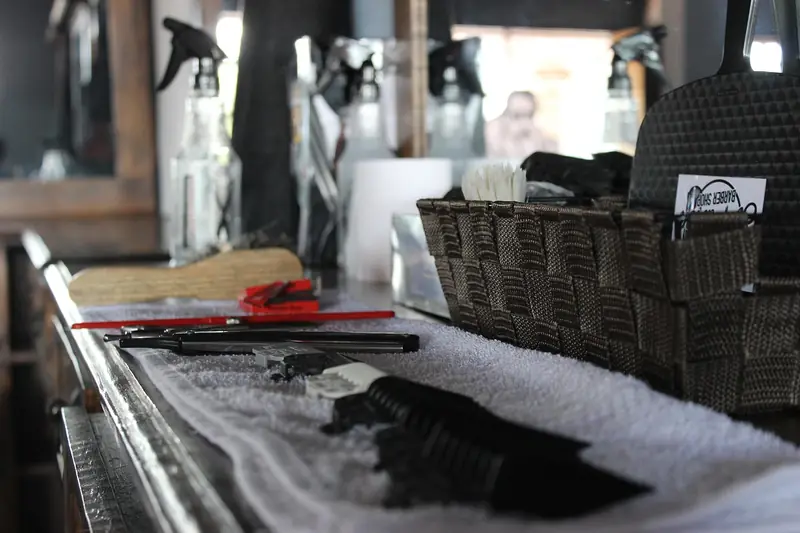 Clippers, combs and a razor laid out on a towel