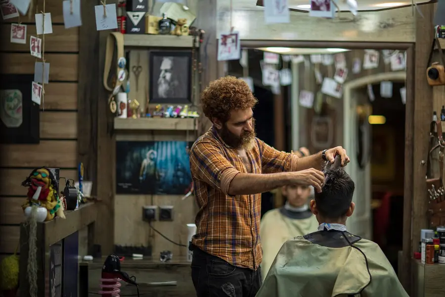 A barber working at the chair with tools hung on the wall behind